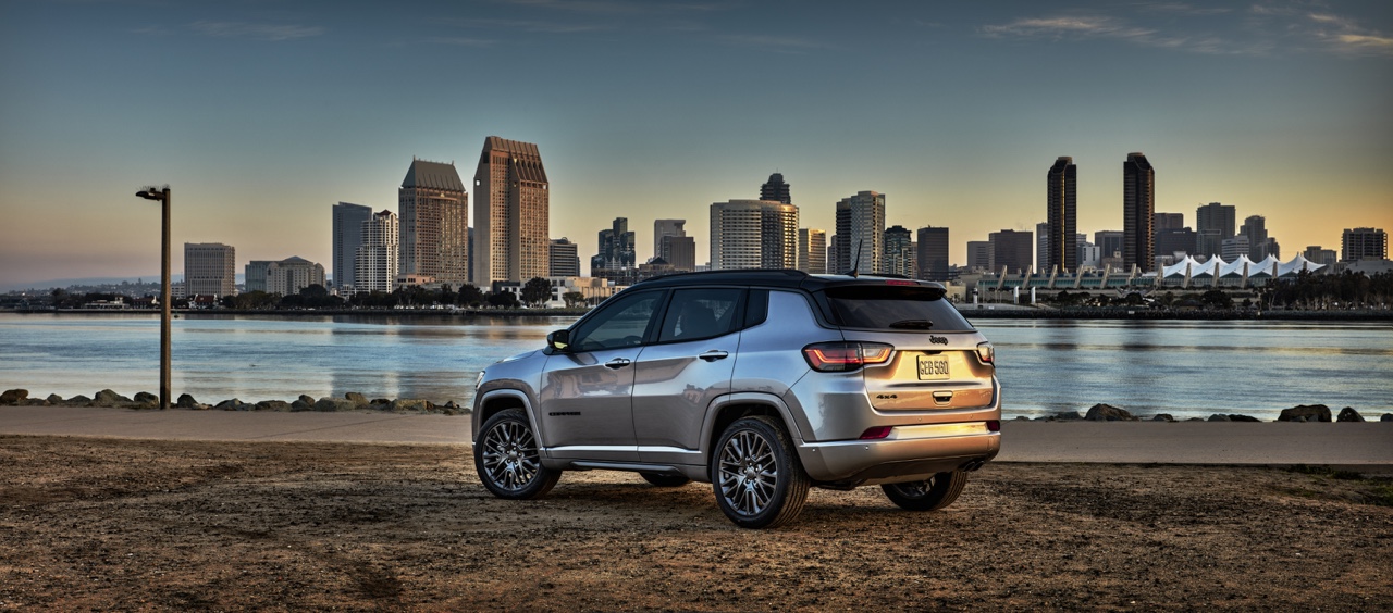 Jeep Compass 2023 gris vu arrière trois quarts stationné en bord de l’eau avec panorama urbain, illustrant le design, la polyvalence et l’usage quotidien du VUS compact.