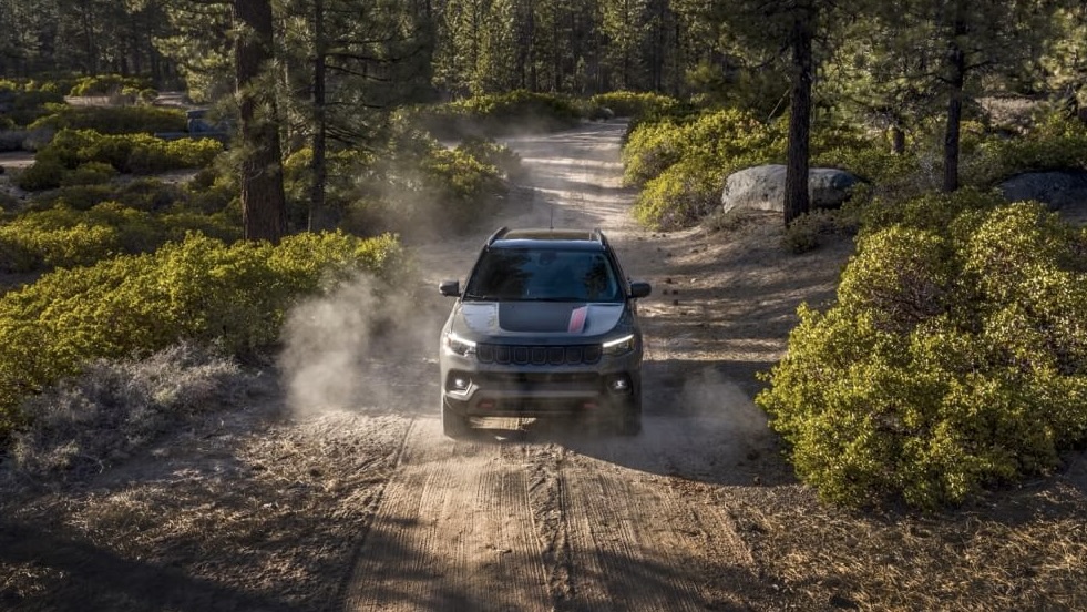 Le Jeep Compass 2024 qui roule sur un chemin de terre en forêt.