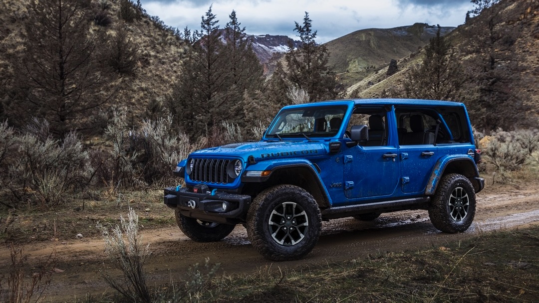 Le Jeep Wrangler 4xe 2024 qui roule sur un chemin de terre en forêt.