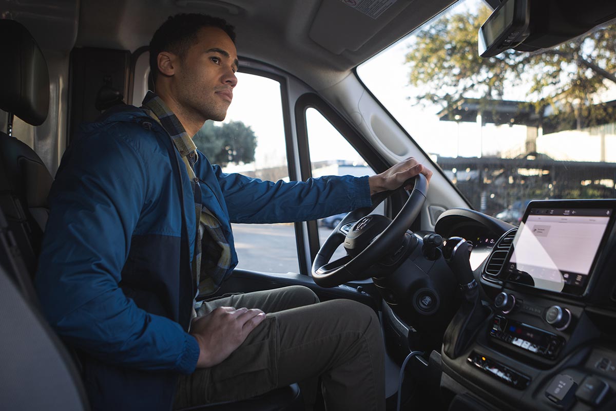 Intérieur de la cabine du Ram ProMaster 2026 avec conducteur au volant, tableau de bord moderne et écran multimédia visible.