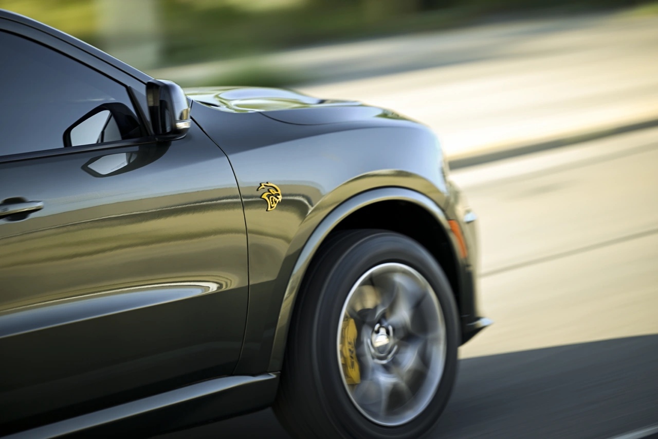 Gros plan sur l’aile avant et la roue du Dodge Durango 2026 SRT en mouvement, avec logo Hellcat visible et arrière-plan flou.