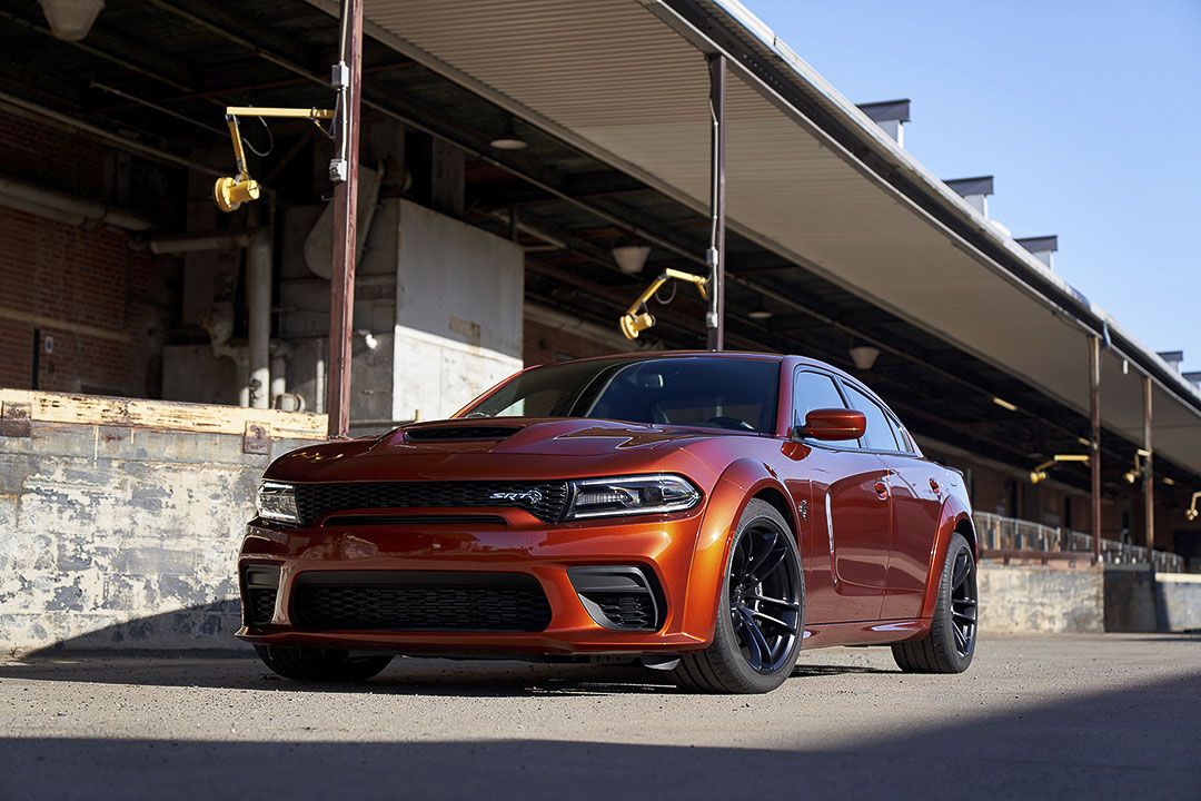 Vue 3/4 avant et latérale du Dodge Charger 2022 en arrêt sur le bord d'un vieux bâtiment