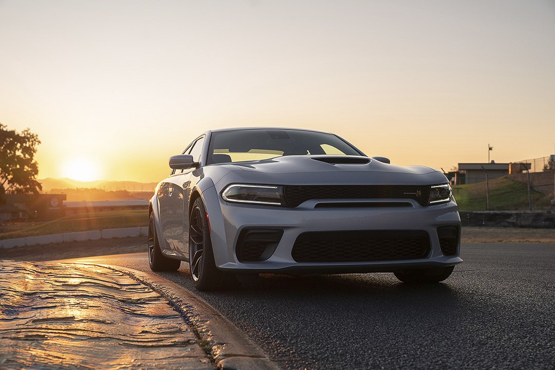 Vue 3/4 avant et latérale du Dodge Charger 2022 sur route avec coucher de soleil