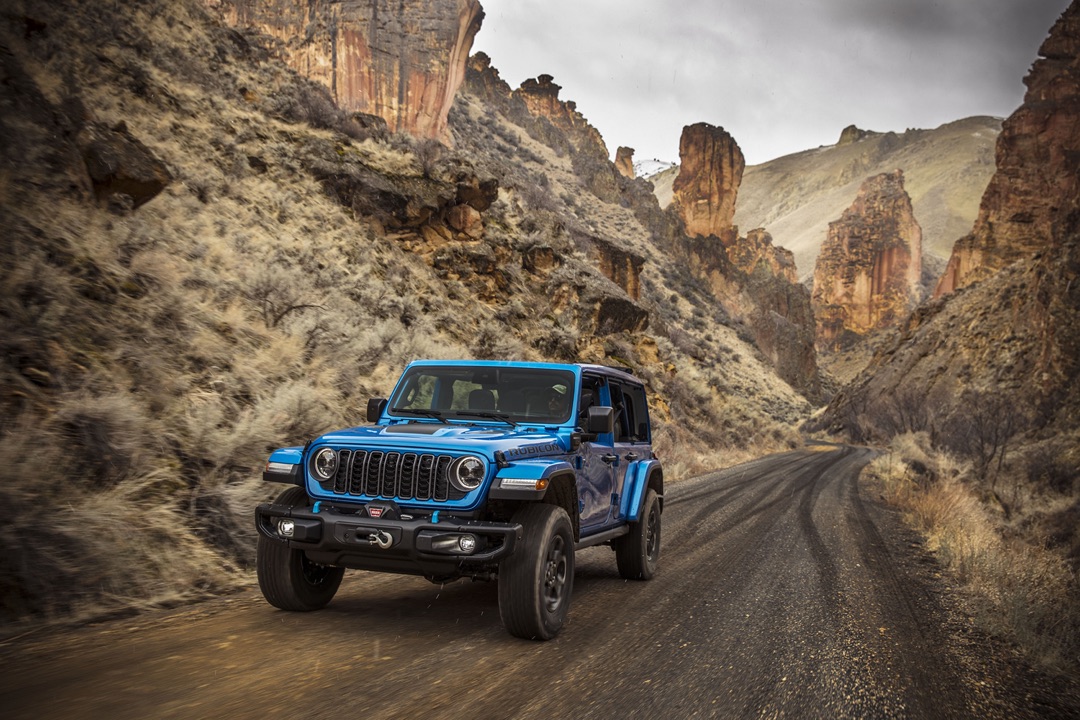 Le Jeep Wrangler 4xe qui roule sur de la gravel entre deux petites montagne.