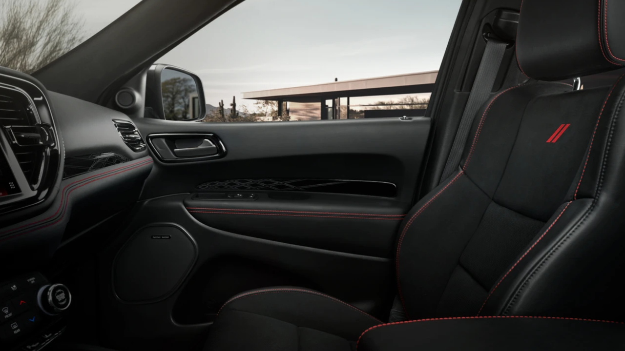 Vue intérieure côté passager avant du Dodge Durango 2026 avec sièges sport en cuir noir et surpiqûres rouges.
