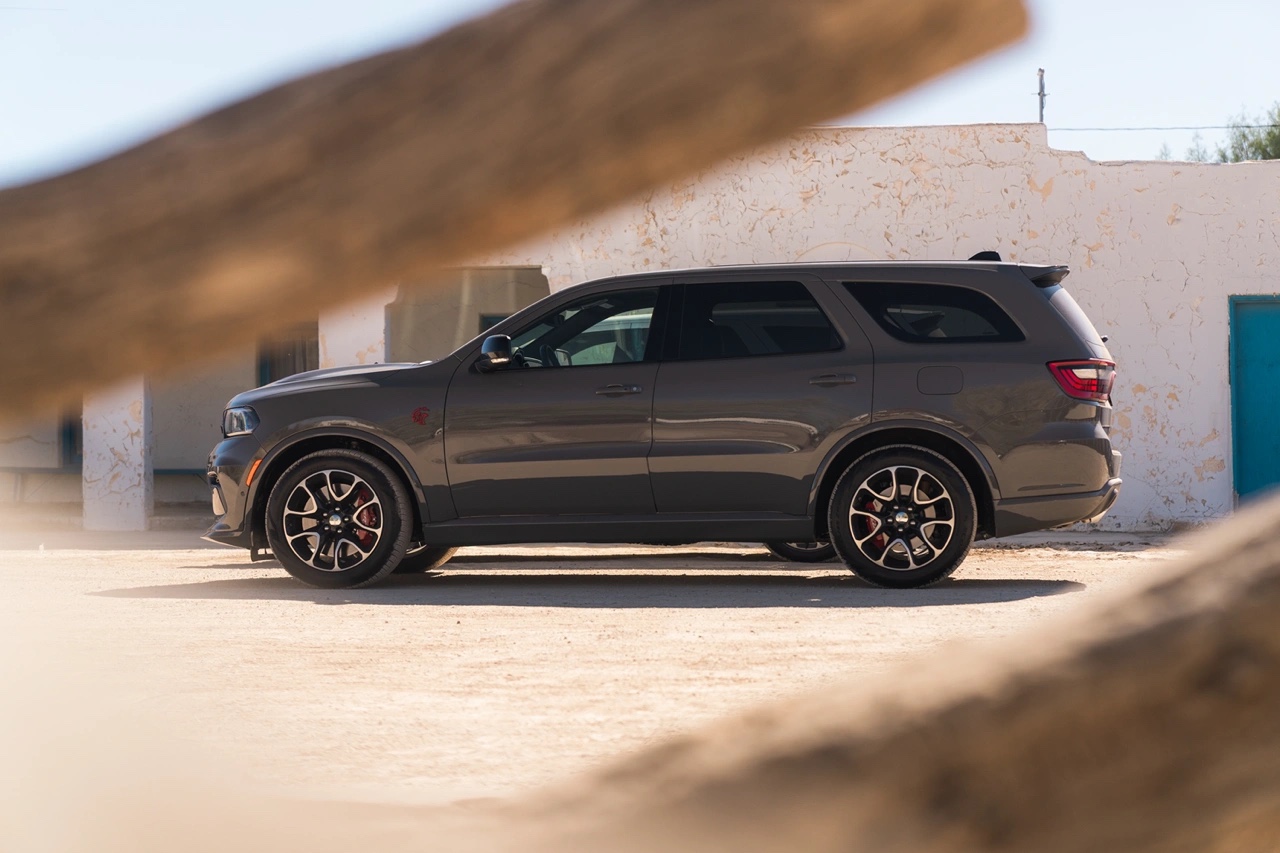 Vue de profil du Dodge Durango 2026 gris stationné dans un décor désertique urbain, mettant en évidence les jantes sport et la silhouette musclée.