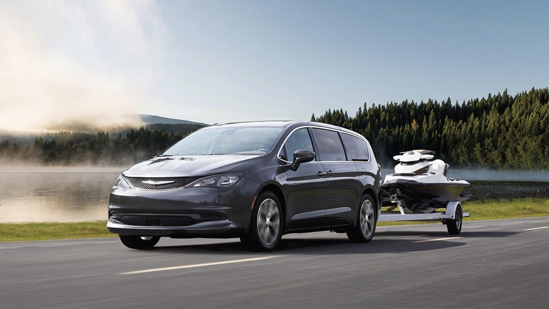 Chrysler Grand Caravan 2024 qui tire une moto marine sur une remorque.