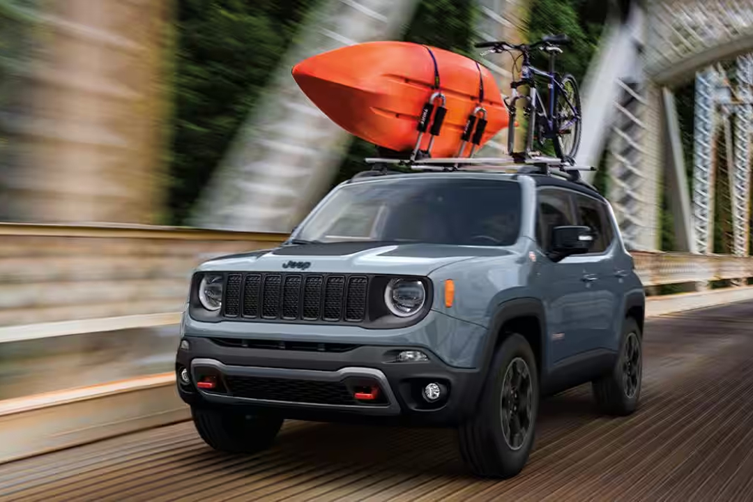 Vue avant et latérale du Jeep Renegade 2023 avec Kayak et vélo sur le toit et traversant un pont