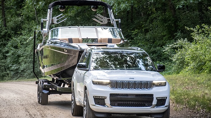 Le Jeep Grand cherokee 2025 qui tire un bateau sur un chemin de gravel.