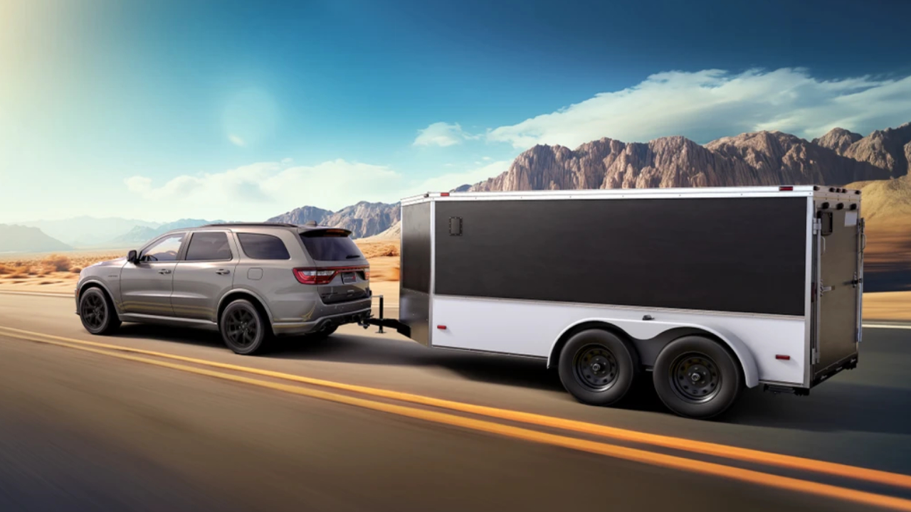 Dodge Durango 2026 gris remorquant une roulotte cargo sur une route désertique, illustrant la capacité de remorquage du VUS.