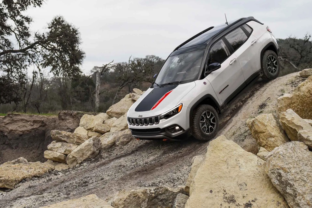 Jeep Compass 2026 blanc en descente sur terrain rocheux, illustrant la version Trailhawk et les compétences hors route du VUS compact.