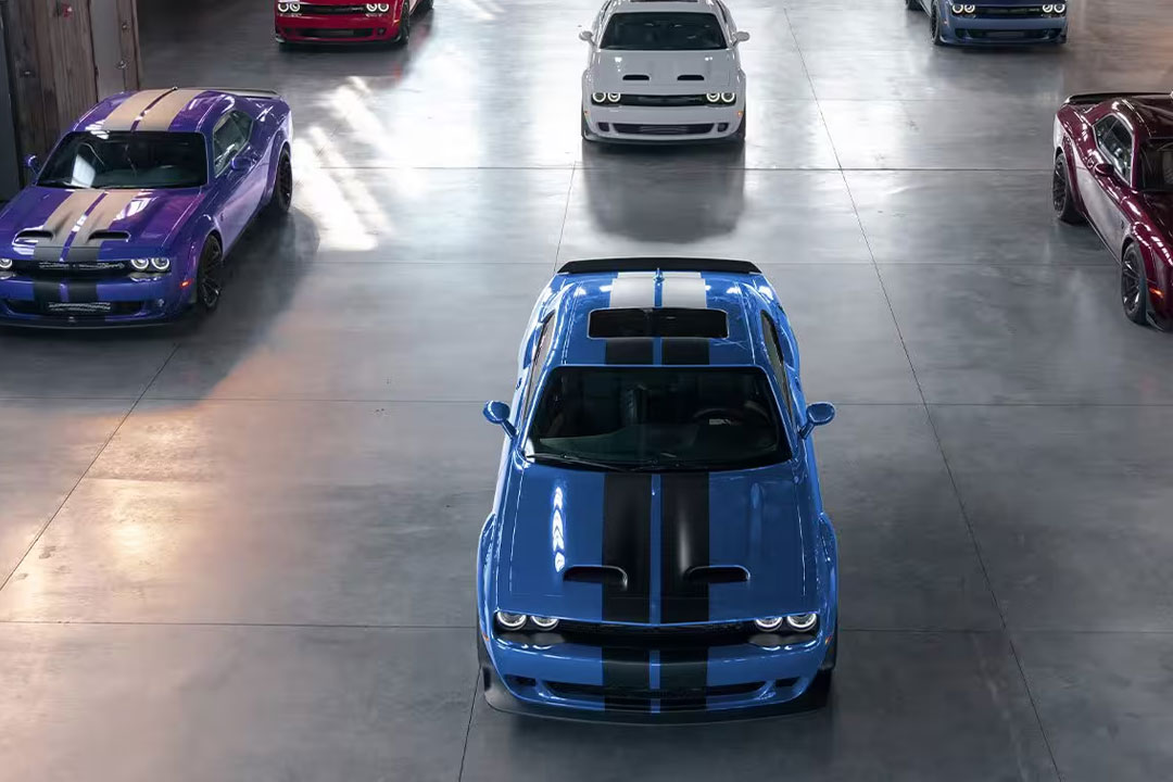 Vue aérienne de plusieurs Dodge Charger 2023 et Challenger 2023 sortant d'une entrepôt