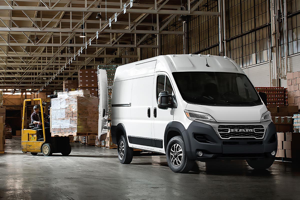 Vue trois quarts avant du Ram ProMaster 2026 blanc dans un entrepôt, illustrant sa capacité de chargement pour la logistique et le transport.