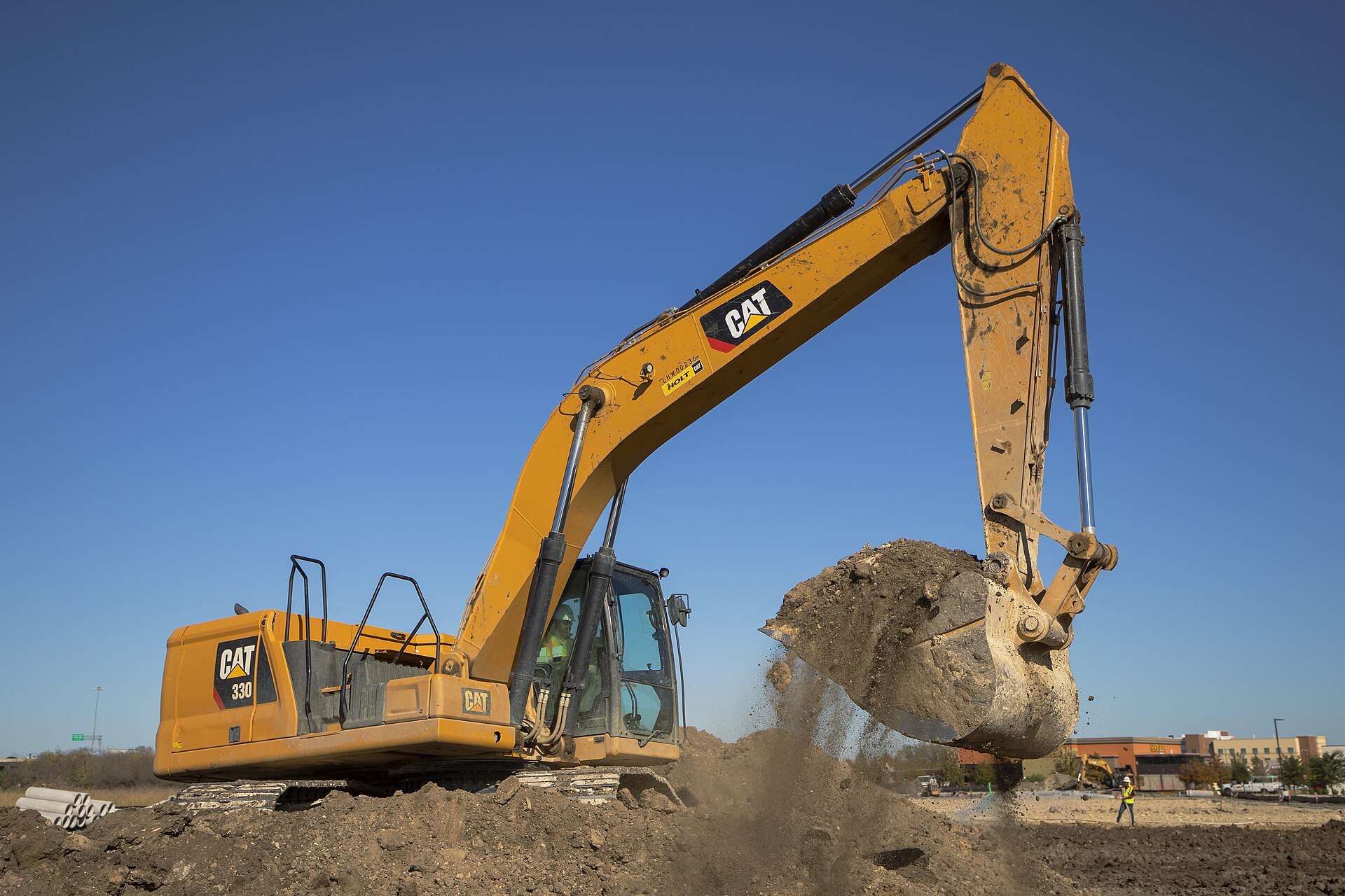 A Caterpillar 330 excavator scooping dirt.