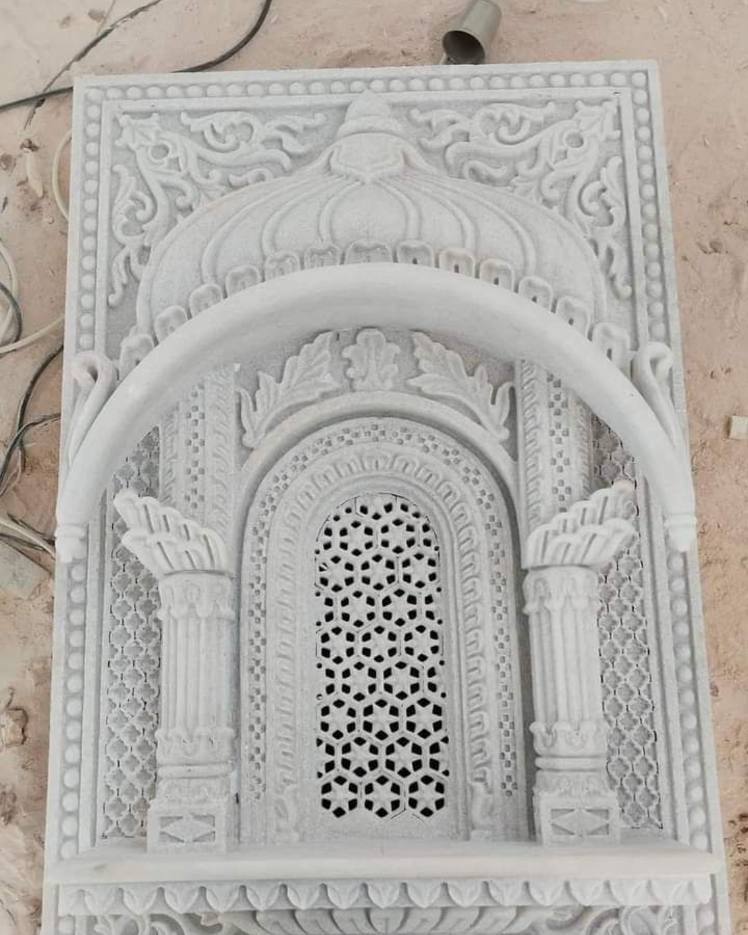 A skilled worker using a tool for intricate detailing on a pillar.