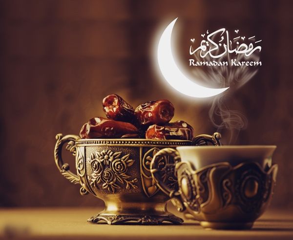 A bowl of dates next to a traditional Ramadan lantern, signifying the breaking of the fast.