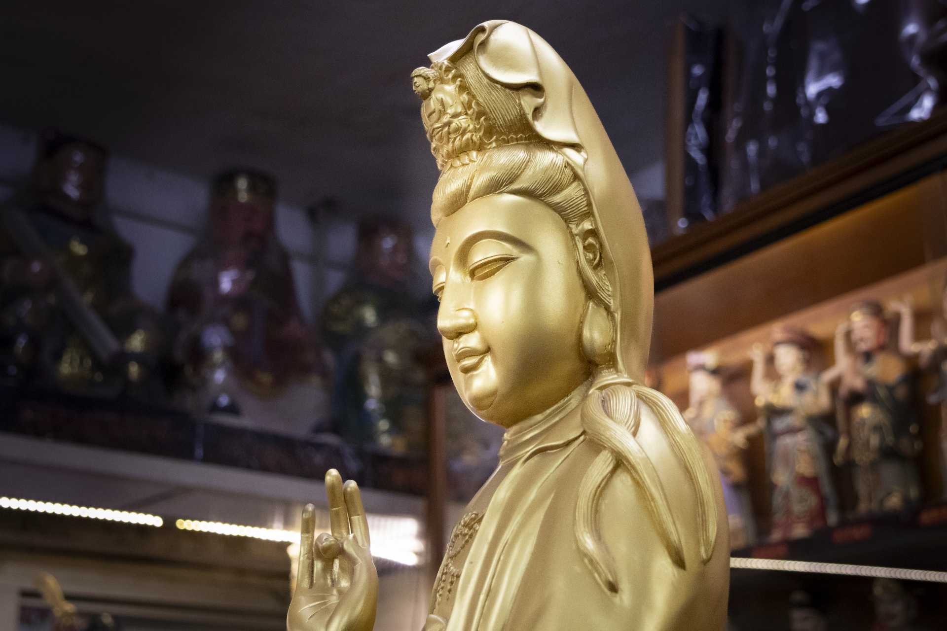 A close-up of a golden Buddha statue with incense.