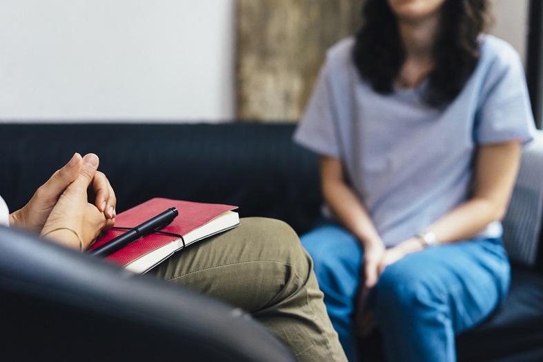 A psychiatrist listens attentively to a patient in a calm office setting.
