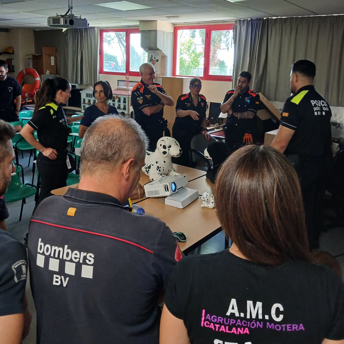 Asistentes a la formación en el aula del parque de bomberos, con un maniquí de perro sobre la mesa