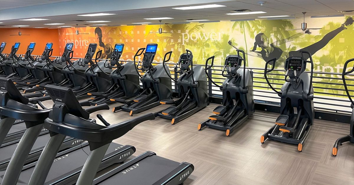 A bright apartment gym with treadmills by a window.