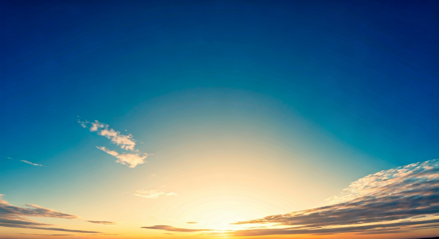 A vast, clear blue sky with a few delicate white clouds, illuminated by soft sunlight. The image captures the serene beauty of the Earth's atmosphere.