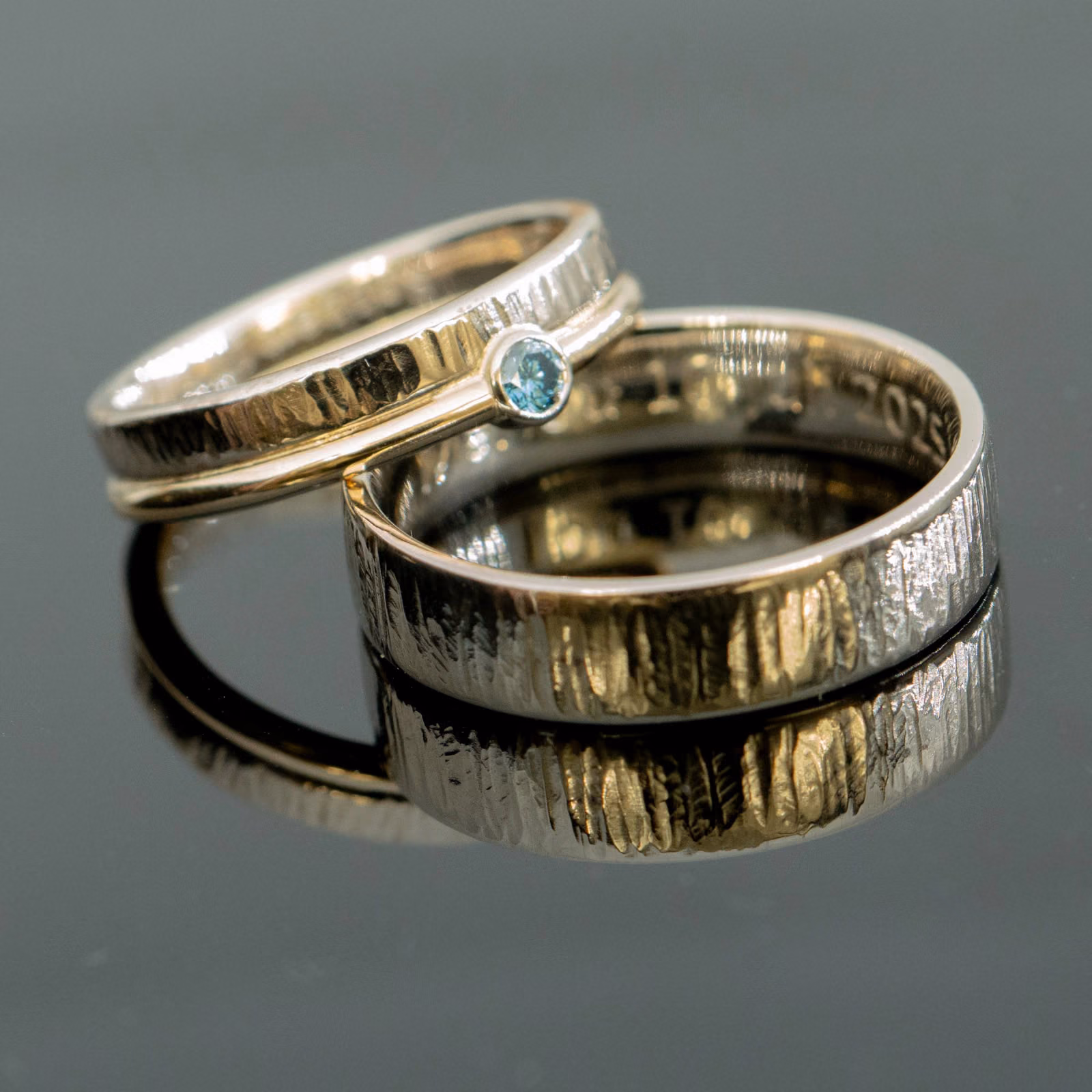 Trouwringen in twee kleuren met hamerslag en blauwe diamant