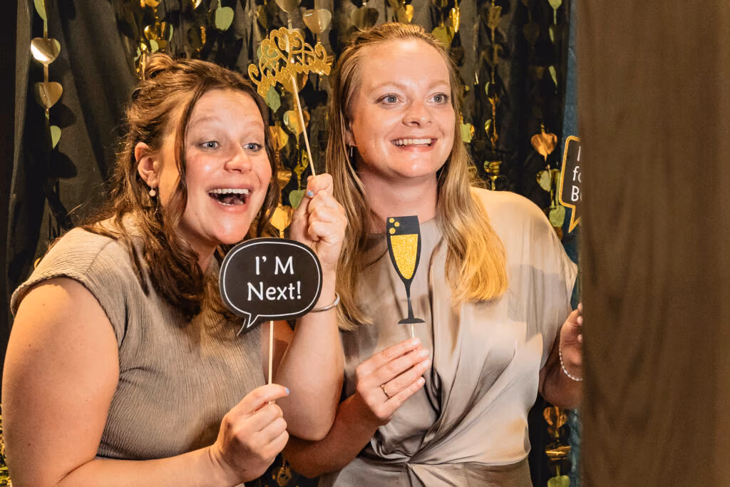 Twee gasten poseren lachend met props voor de photobooth van Ja, IK lach