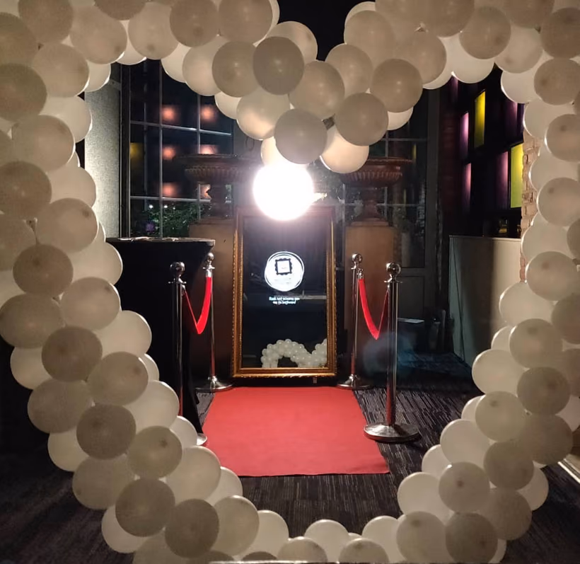 Spiegel-photobooth van Ja, IK lach opgesteld achter een ballonboog op een feest