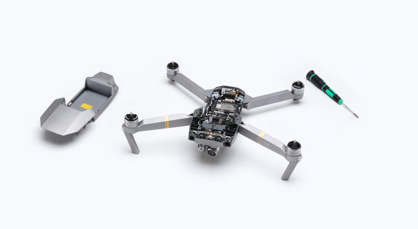 A technician in a lab coat inspecting the internal components of a drone.