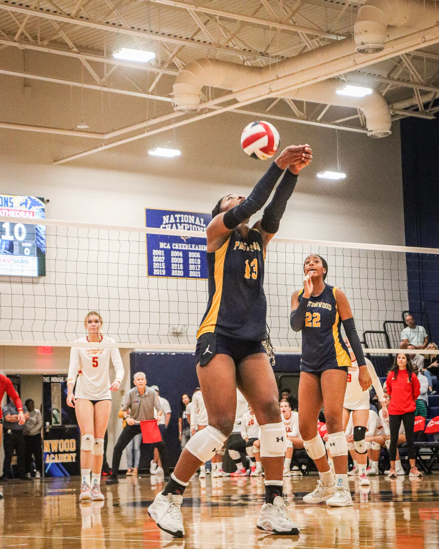 A group of athletes mid play during a volleyball game, under floodlights.