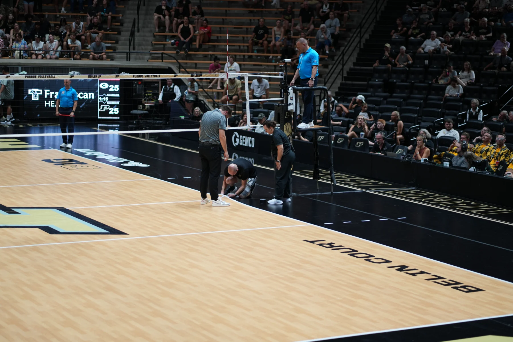 Officials and crew gather at the net post during a stoppage on Purdue's Belin Court.