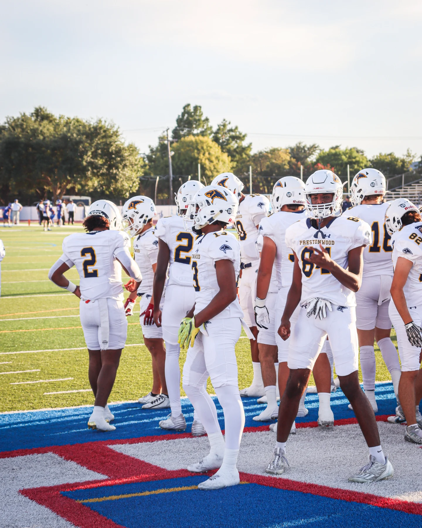 Prestonwood players in white jerseys gather in the end zone under late afternoon light.