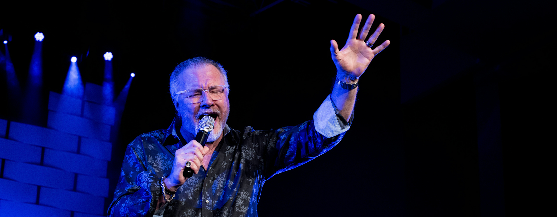 A worship leader singing on stage with a band.