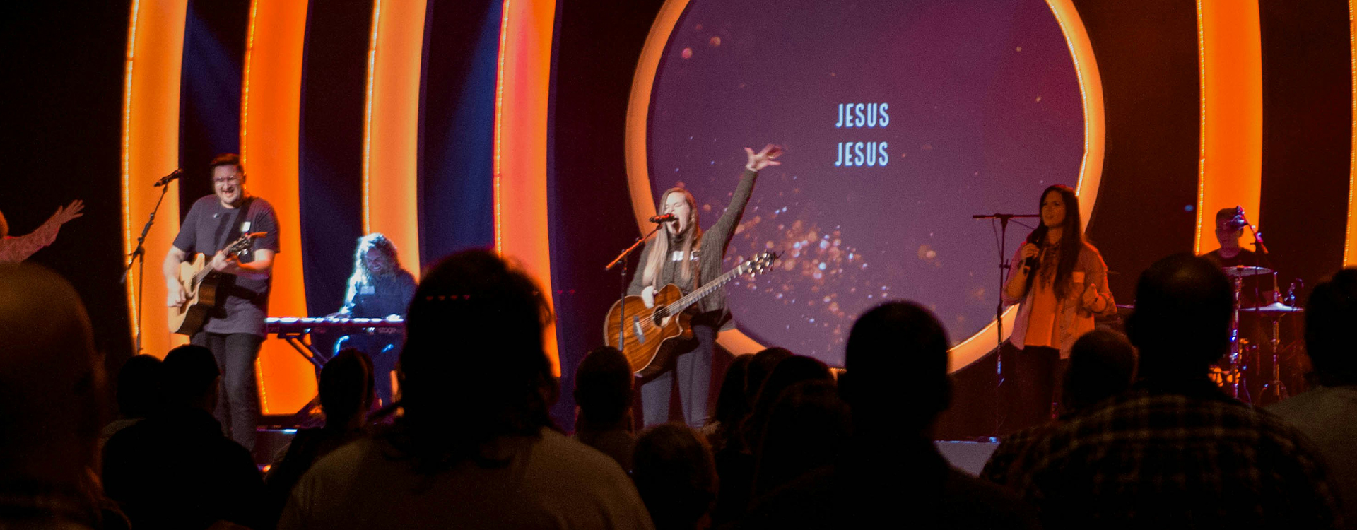 A wide shot of a congregation worshiping in a modern church.