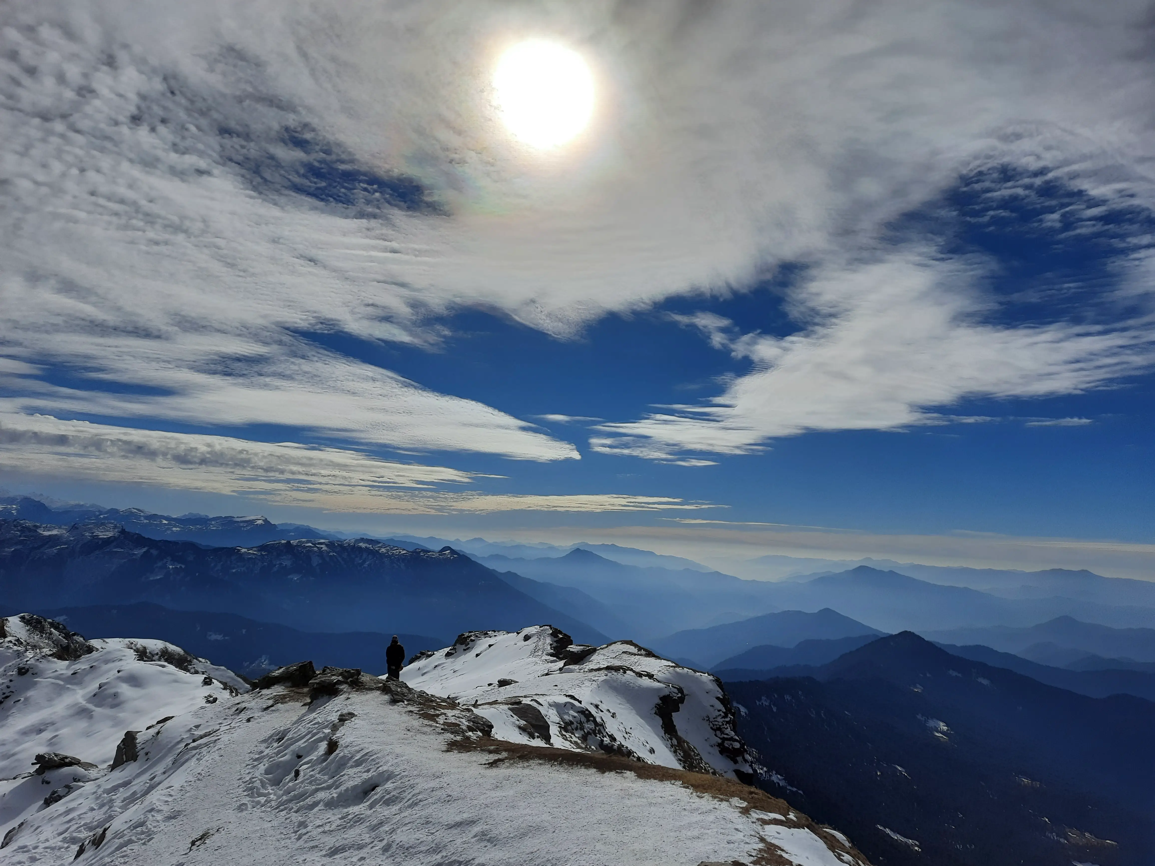 Light pours across ridges and tents rest briefly below. Here, shelter is temporary and the sky decides the rules.