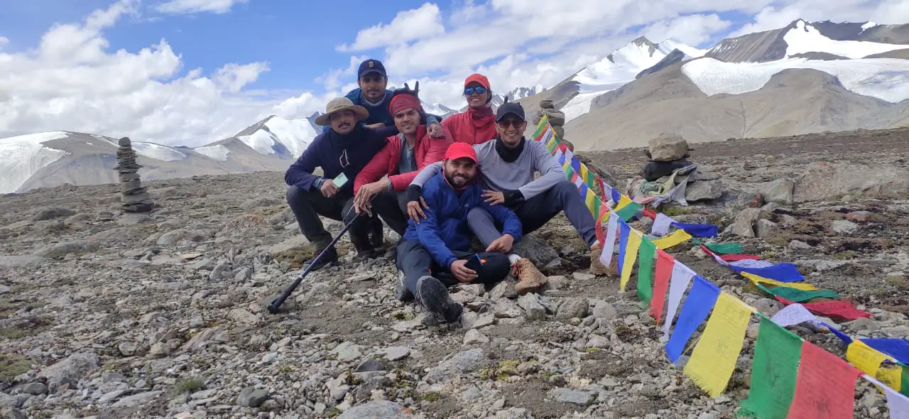 A group of climbers resting near prayer flags after a demanding ascent, capturing camaraderie and achievement at extreme altitude.