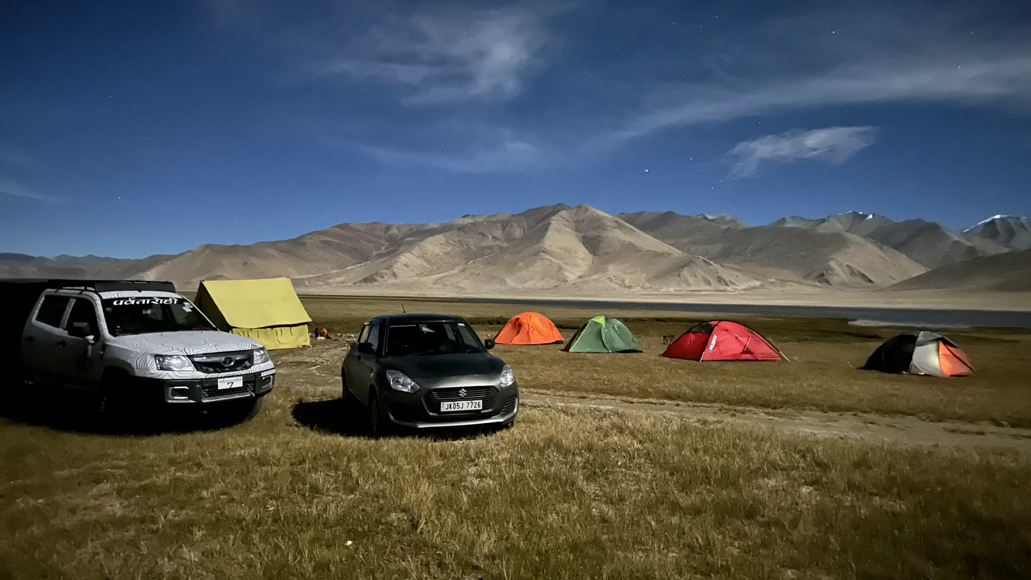 A tent at the Kiagar Ri base camp with prayer flags and the peak in the background.