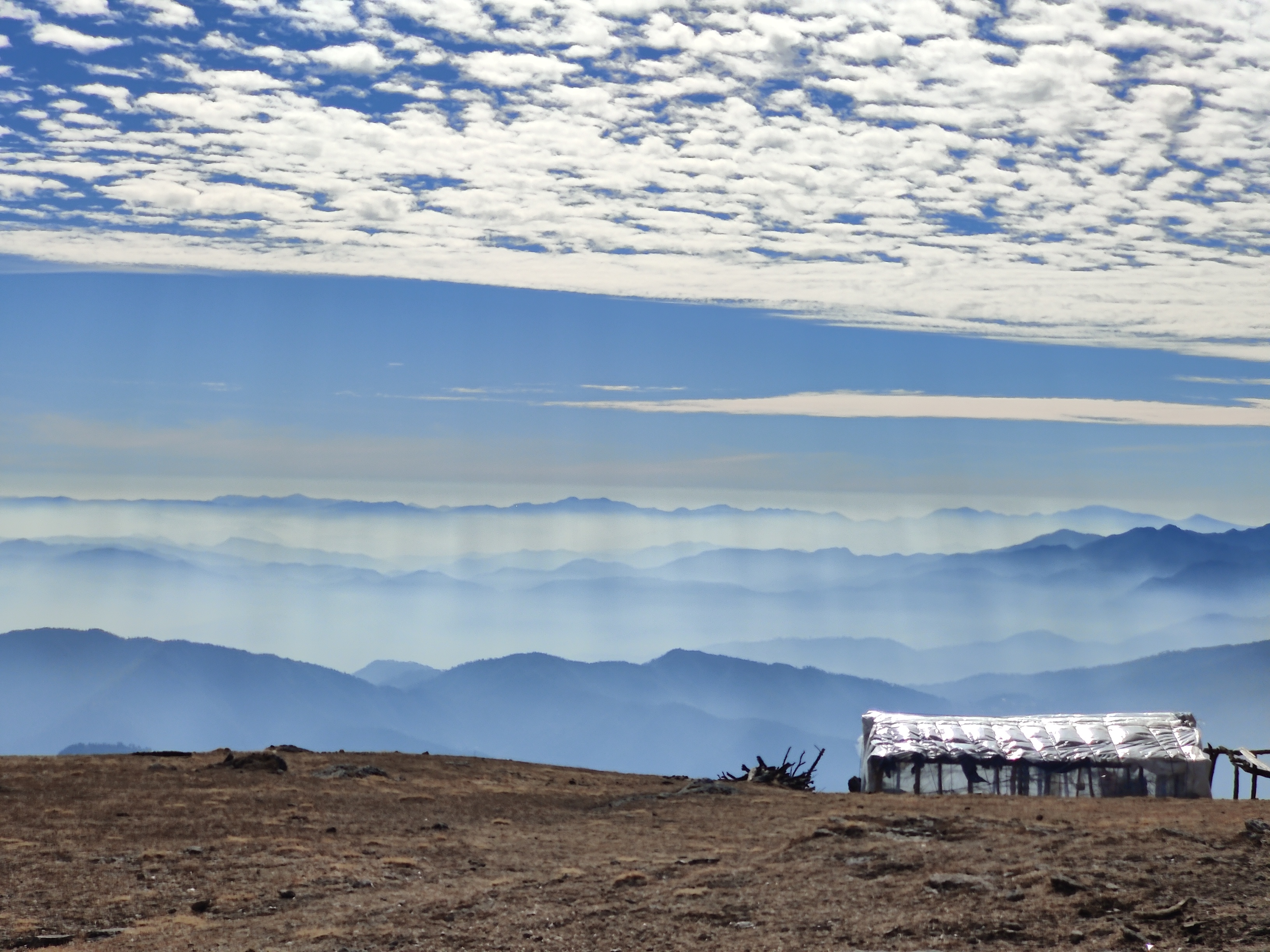 Panoramic view from the summit of brahmatal, showing the vast Himalayan landscape.