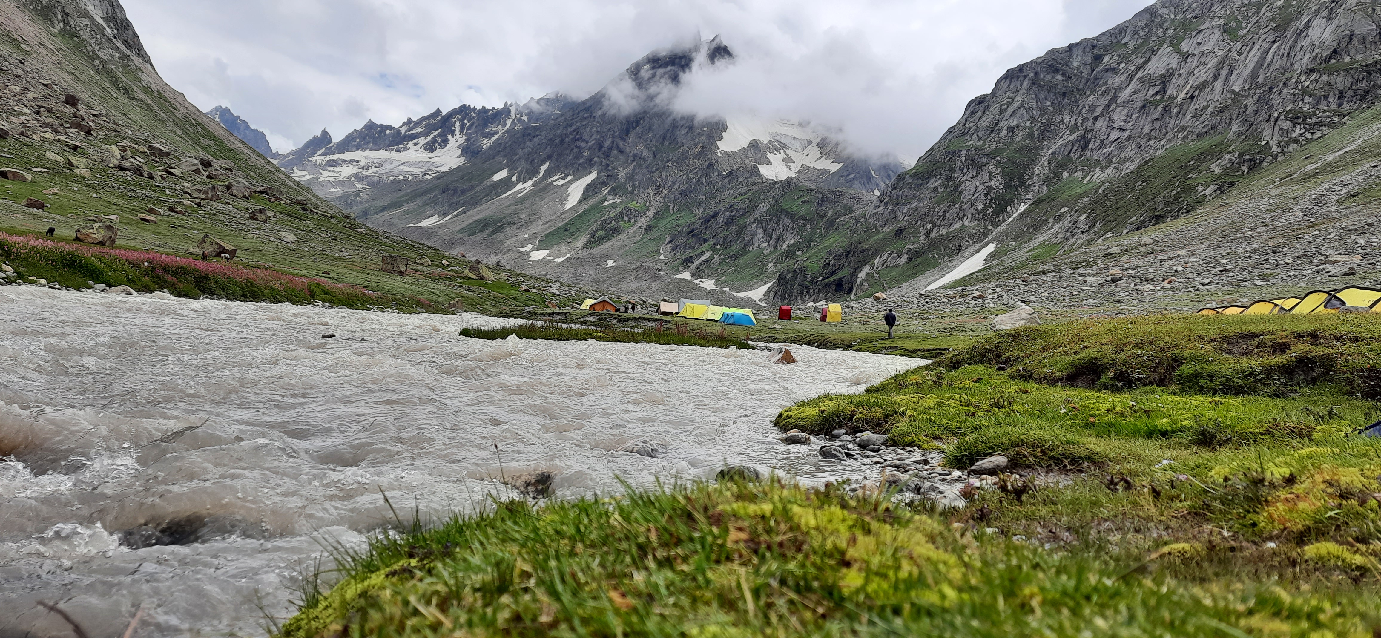 A tent at the hampta pass base camp with prayer flags and the peak in the background.