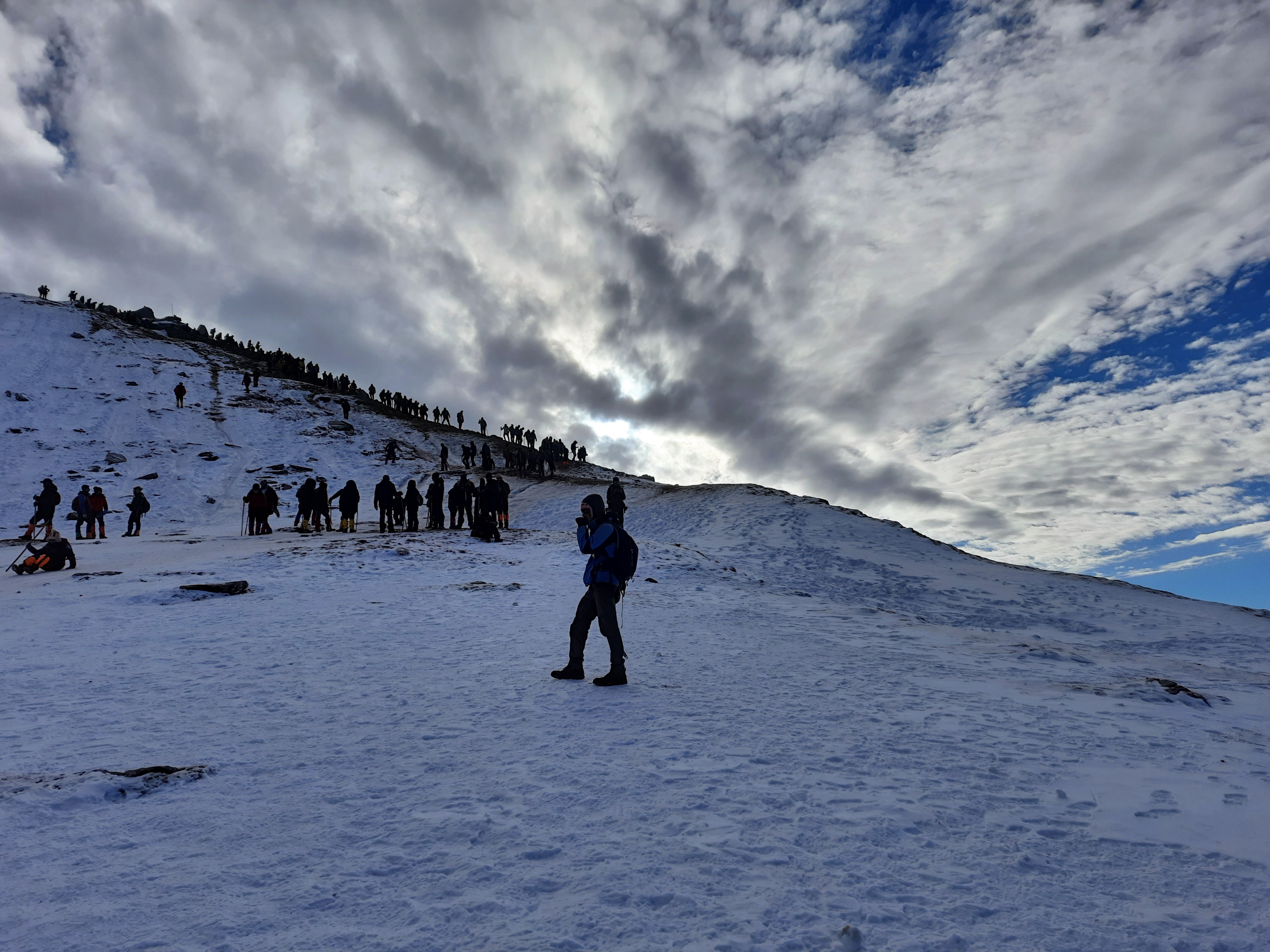 Climbers making their way up a snow-covered ridge towards the Kedarkantha summit.