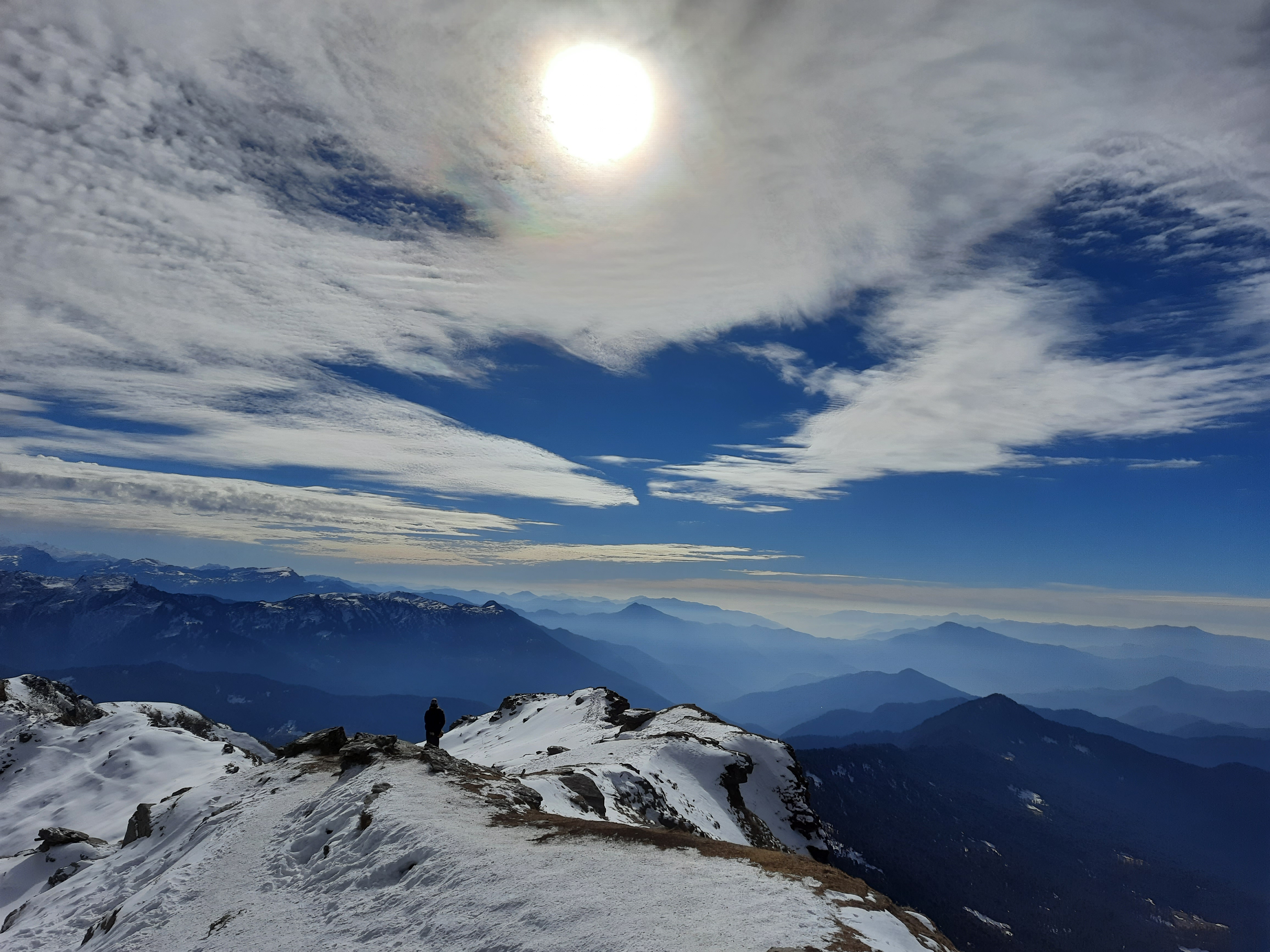 A tent at the Kedarkantha base camp with prayer flags and the peak in the background.