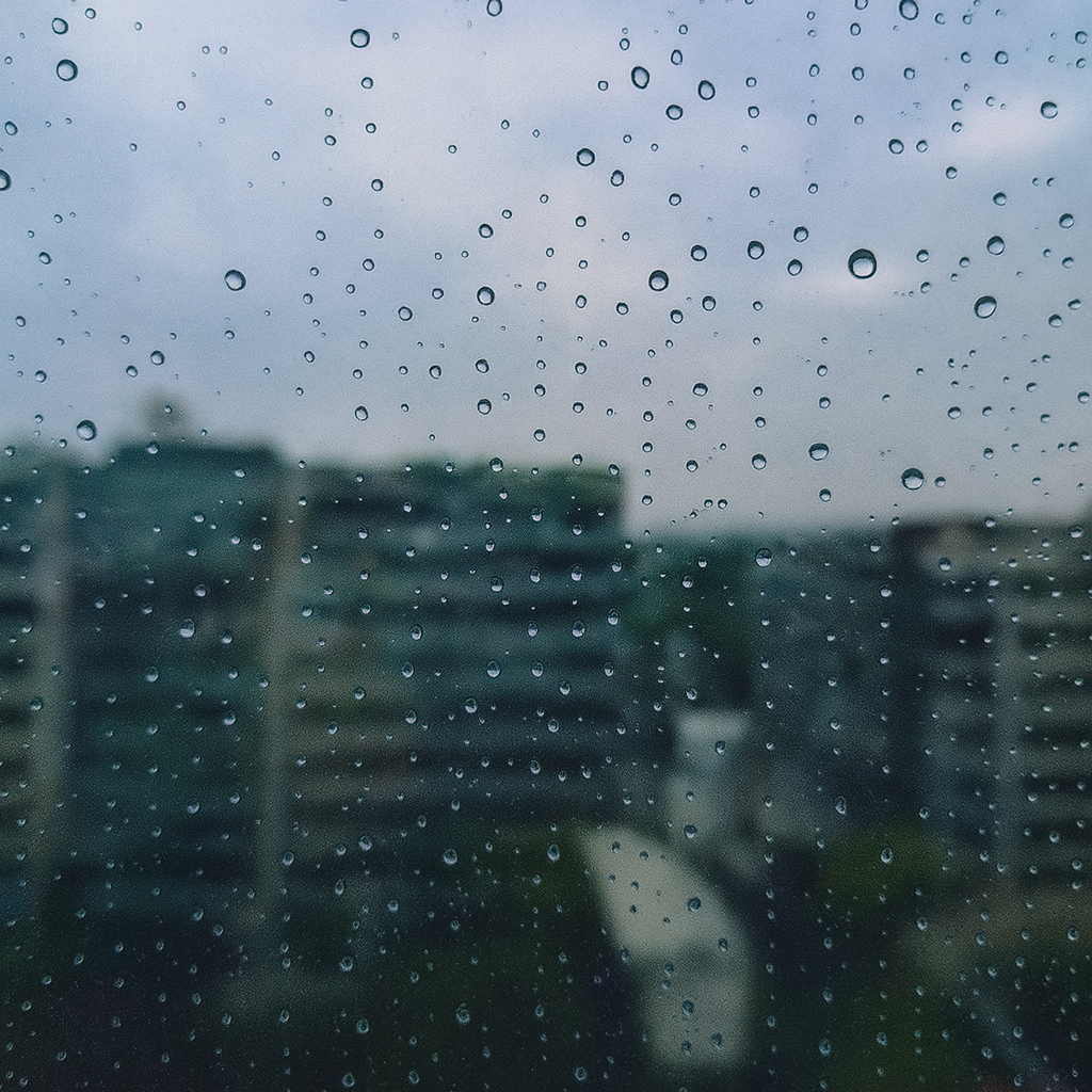 Raindrops cling to glass like thoughts we never voice. The blurred skyline becomes a metaphor for a mind lost between the world outside and the storm within.
