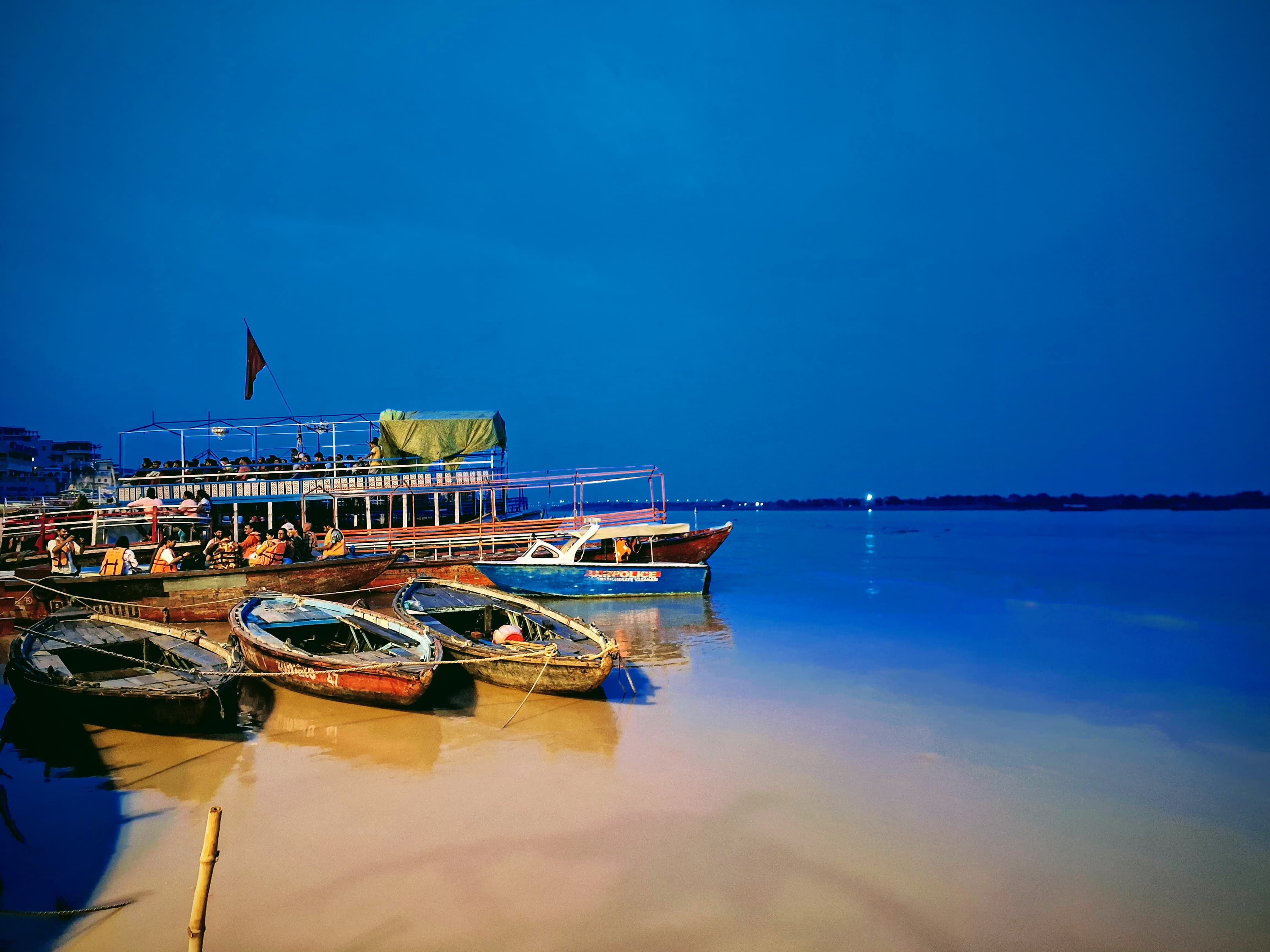 Boats rest along the ghats as night falls — an image of harmony, stillness, and continuity. The river holds the day’s weight and releases it into silence.