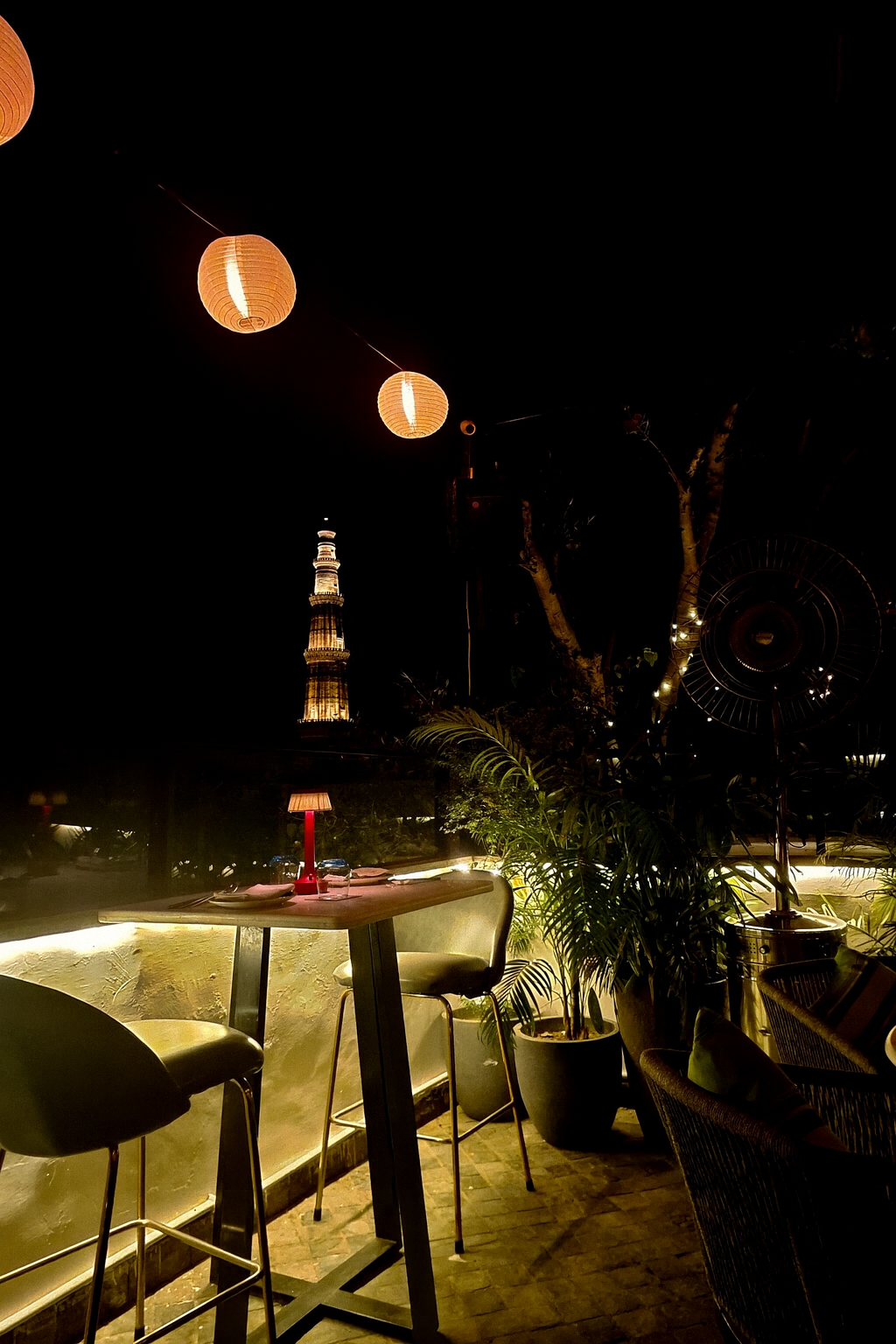 Two empty chairs and a distant tower — symbols of waiting, intimacy, and the quiet warmth of human presence. The light is soft, yet it reveals the ache of distance.