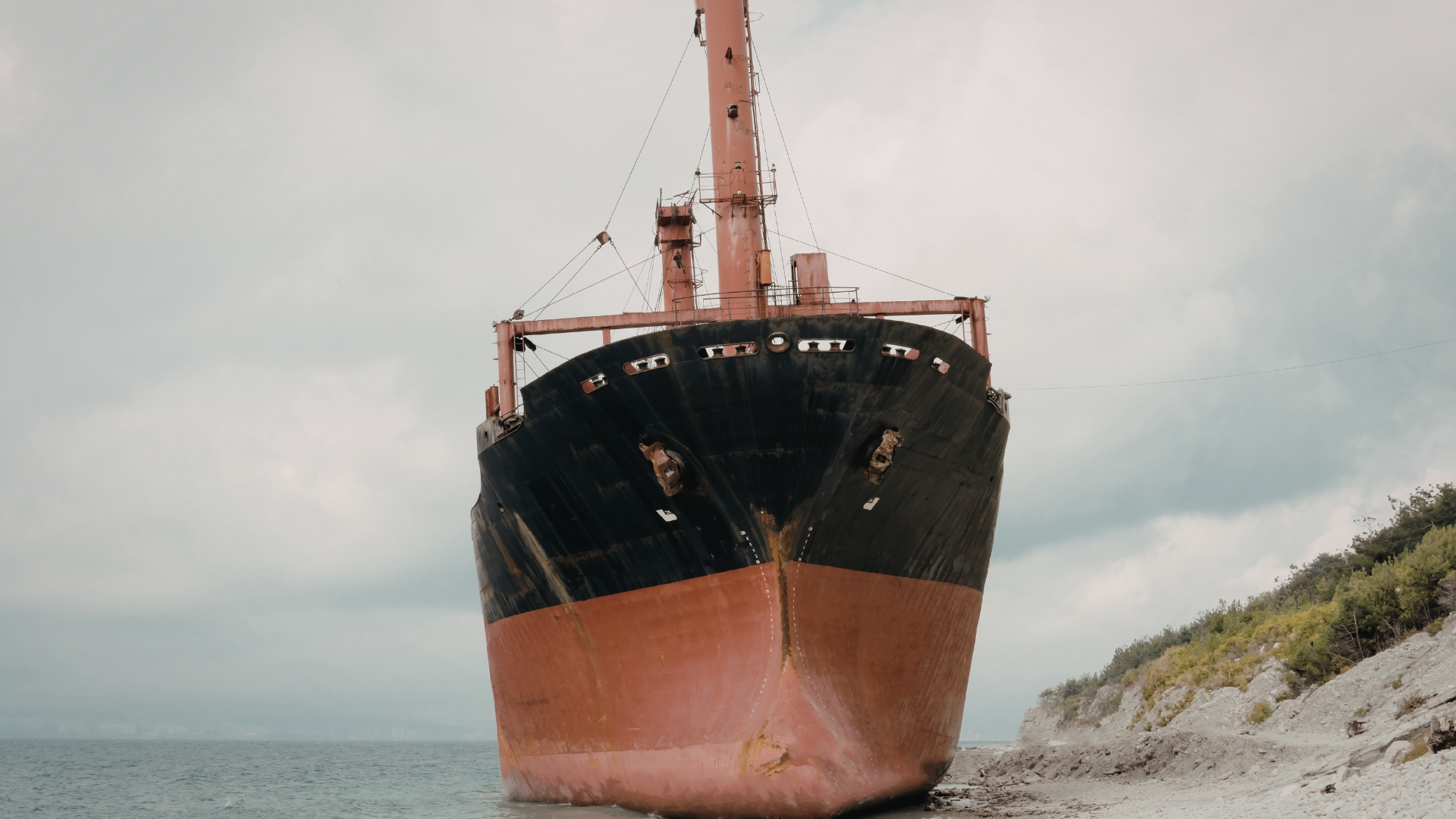 Workers cleaning the hull of a large ship.