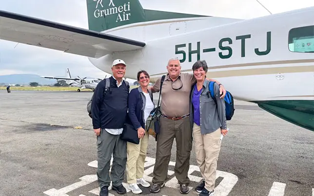 Happy tourists posing in front of a Ruka Africa plane at an airstrip.