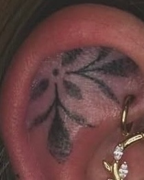 Dieses zarte Tattoo im Ohrbereich besticht durch feine Linien und geschickte Schattierungen, die eine harmonische Floral-Ästhetik erzeugen. Die filigranen Blätter und die subtile Platzierung machen es zu einem einzigartigen Hingucker, der Eleganz und Individualität ausstrahlt.