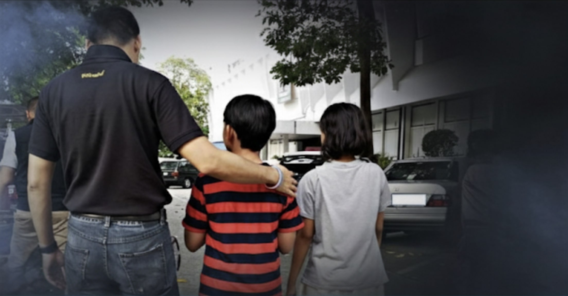 An adult with a comforting hand on the shoulder of two children.