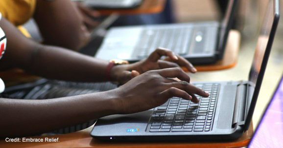 A person working on a laptop with code on the screen.