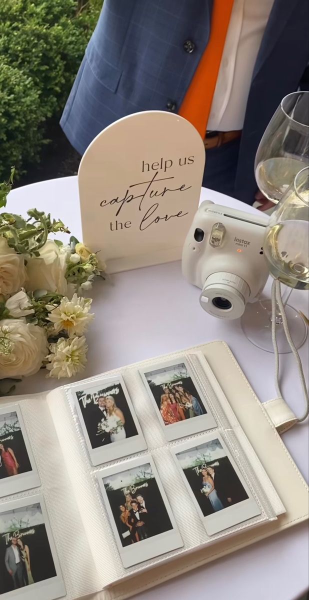 A smiling couple holding instant prints at their wedding.